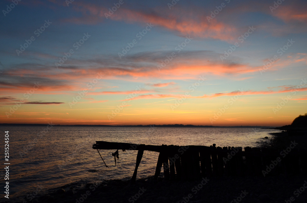 Sunset over the see seen trough silhouettes of a decayed groyne