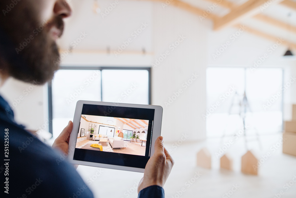 Fototapeta premium Midsection of man with tablet, looking at interior design sketches. A new home concept.