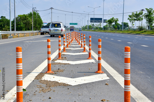 Orange traffic pole or flexible traffic bollard on asphalt road for crossroad.