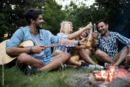 Friends playing music and enjoying bonfire in nature