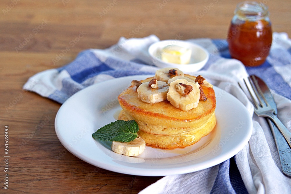 Cornmeal pancakes on a white plate. Served with bananas, walnuts and honey or maple syrup. Cornmeal pancakes on a white plate. Served with bananas, walnuts and honey or maple syrup.