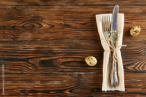 Table setting arrangement in minimal style with easter spring holiday attributes, fork, knife and napkin. Background, copy space, close up, flat lay, top view.