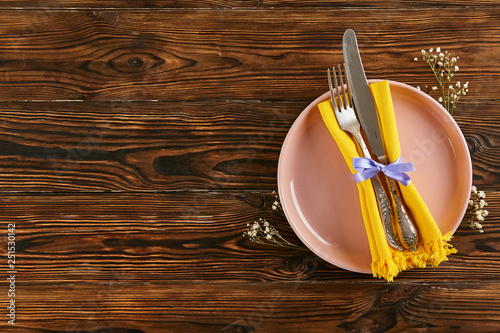 Table setting arrangement in minimal style with easter spring holiday attributes, fork, knife and napkin. Background, copy space, close up, flat lay, top view.