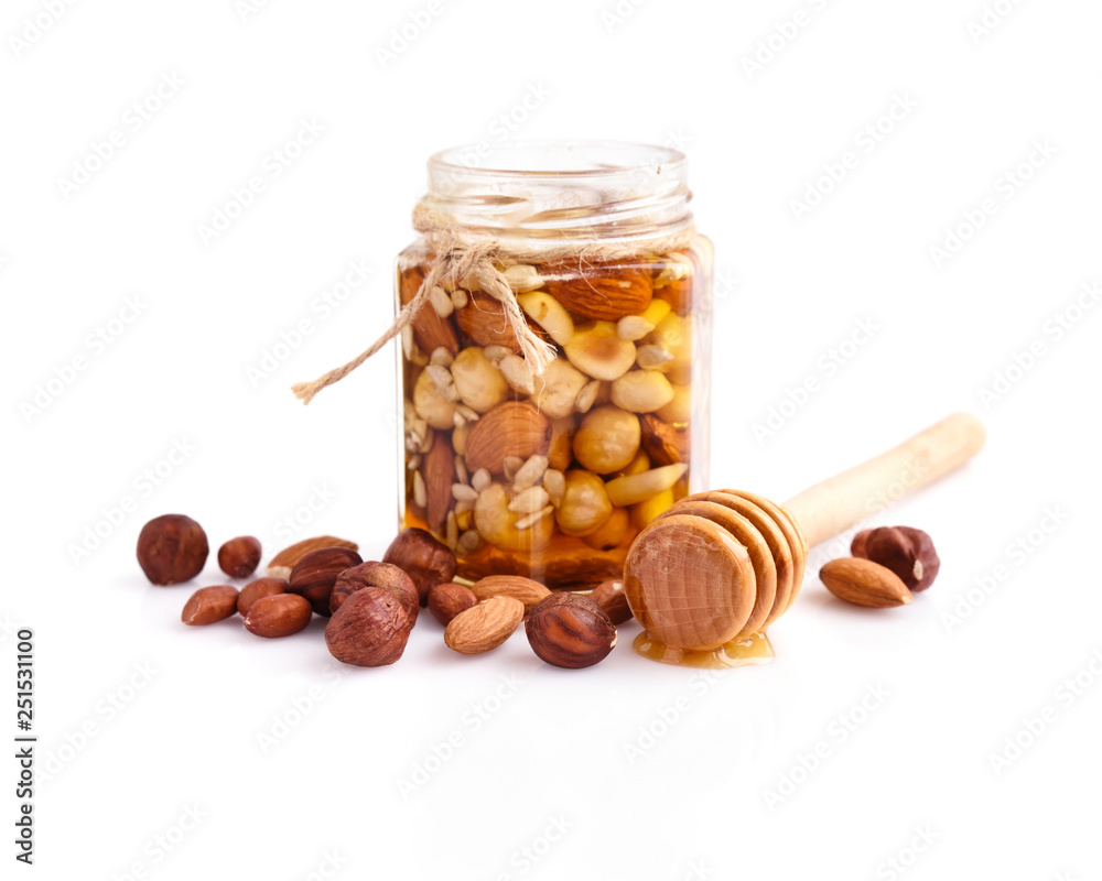 A honey jar with a spoon for honey and different nuts on white background  Stock Photo