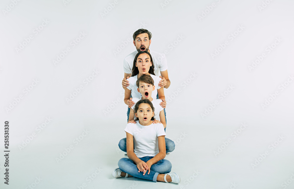 It's impossible! Very surprised family with opened mouths looking on camera isolated on white in T-shirts - obrazy, fototapety, plakaty 