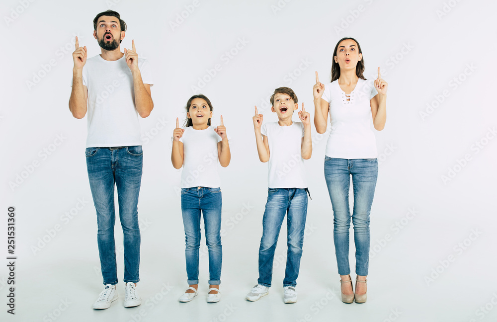 Beautiful family standing in line and pointing up and shouting isolated on white background Beautiful family standing in line and pointing up and shouting isolated on white background