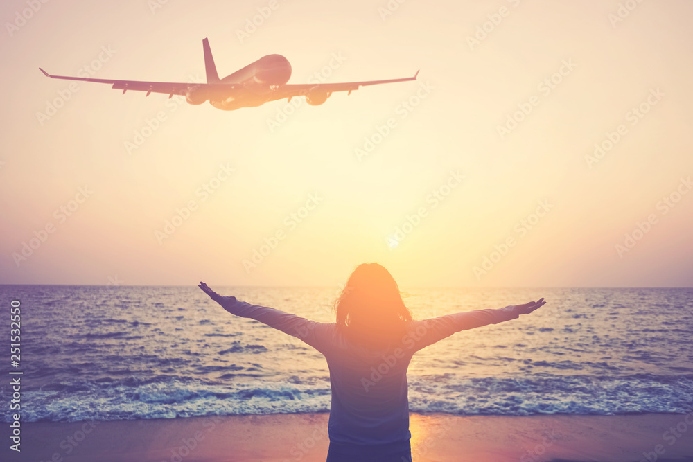 Airplane flying over woman rise hand up on sunset sky at beach and island background.