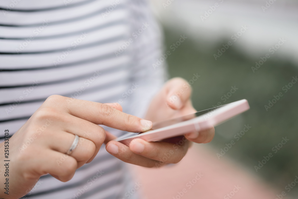 Close up woman hand hold using smart phone on outdoor park street background.