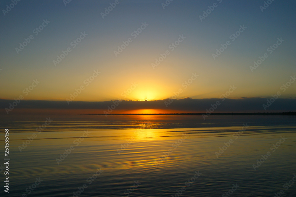 sunrise on a big lake. The sun's rays shine through the clouds