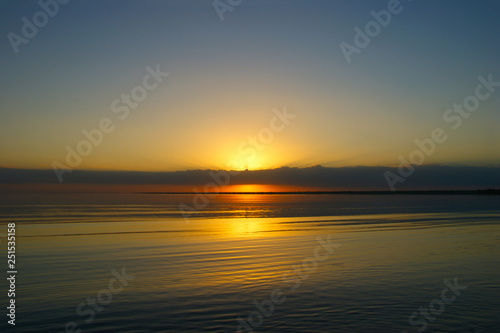 sunrise on a big lake. The sun's rays shine through the clouds © Otar