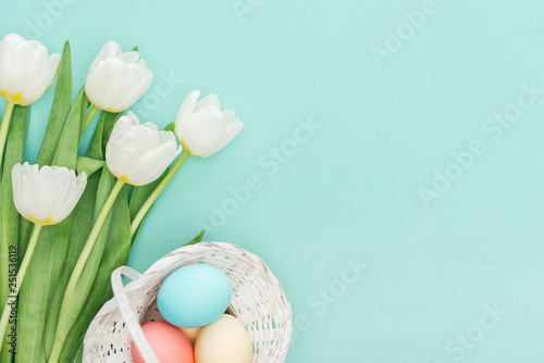 Canvas Print Top view of tulip flowers and easter eggs in wicker basket isolated on blue with