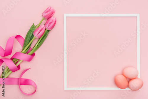 top view of pink tulips with ribbon and easter eggs with frame isolated on pink