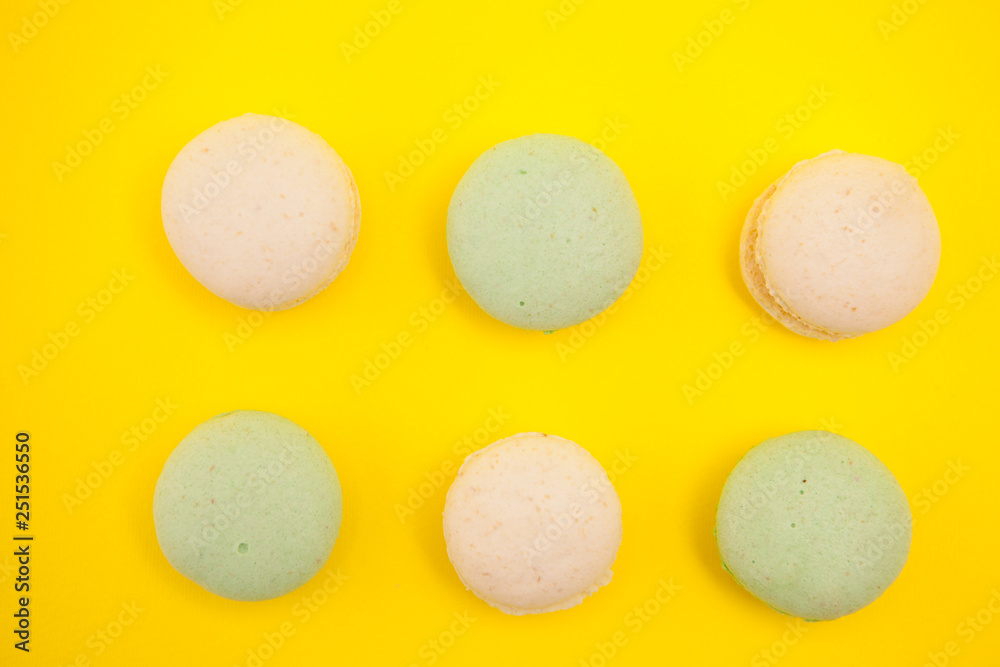 Fototapeta premium Top view of Peach and green tee macaroons in rows over yellow background