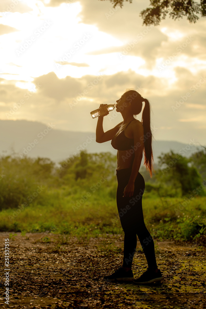 Sport asian girl drinking water from recycled plastic bottle in the mountains in the evening. Sport asian girl drinking water from recycled plastic bottle in the mountains in the evening.