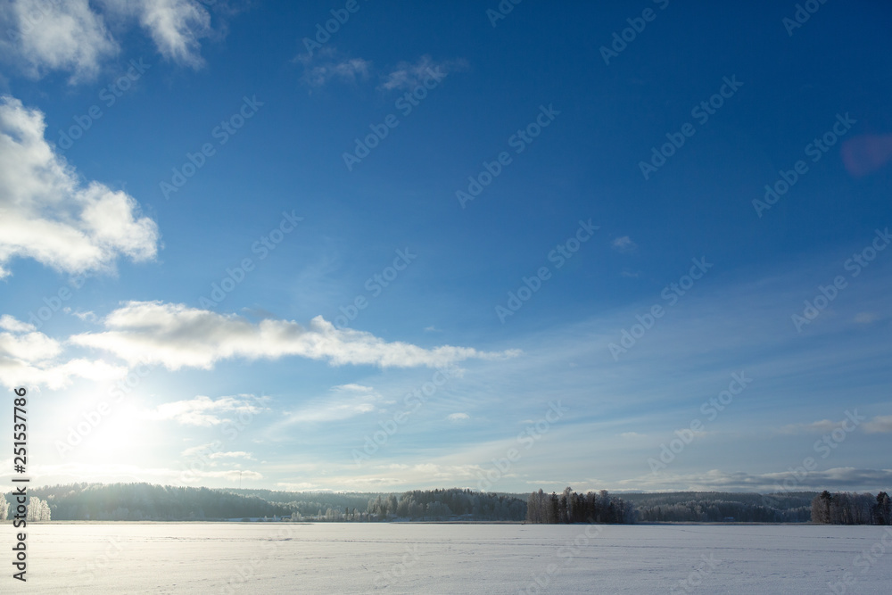 Winter wonderland view on the lake ice on a cold winter morning in Finland. Blue sky and sunrise in January.