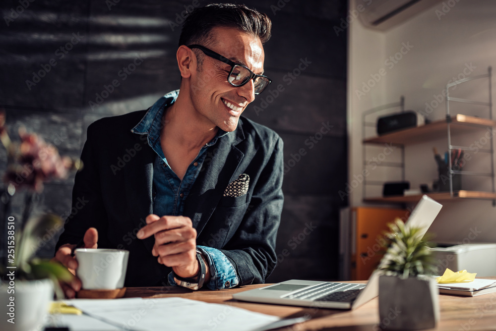 Businessman drinking coffee and using laptop with a smile Businessman drinking coffee and using laptop with a smile