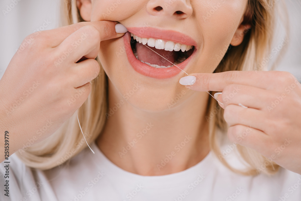 cropped view of woman flossing teeth with dental floss cropped view of woman flossing teeth with dental floss