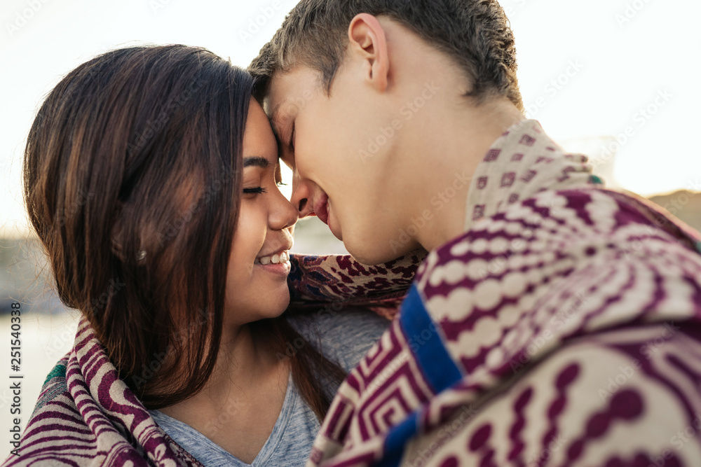 Young couple kissing while wrapped in a blanket together outside Young couple kissing while wrapped in a blanket together outside