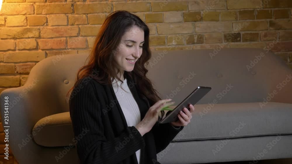 Young caucasian girl with wavy hair sitting on floor watching into tablet and shows green screen of it in cosy home atmosphere. Young caucasian girl with wavy hair sitting on floor watching into tablet and shows green screen of it in cosy home atmosphere.
