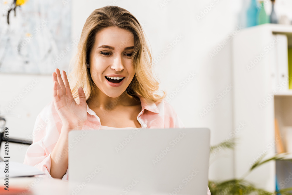 Excited girl looking at laptop screen and waving hand Excited girl looking at laptop screen and waving hand