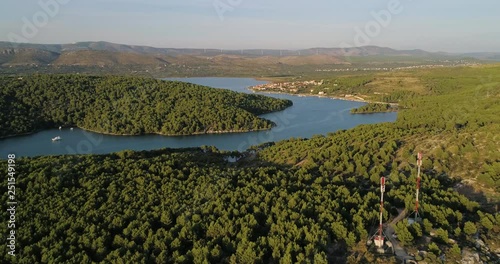 Mediterranean river, C4k aerial, tracking, drone shot, of a boat on morinje lake, on the croatian shore, overlooking the Jadrtovac village, on a sunny, summer evening, in Croatia photo