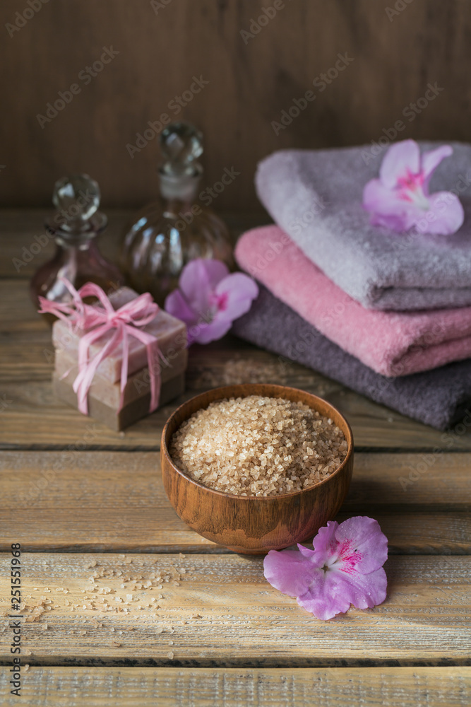 Sea salt, natural handmade soap, natural cosmetic oil and colorful towels with azalea flowers on rustic wooden background Sea salt, natural handmade soap, natural cosmetic oil and colorful towels with azalea flowers on rustic wooden background