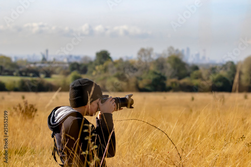 Teenage boy taking photos with dslr camera in a nature reserve