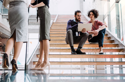 Group of young businesspeople stitting on a staircase, talking. photo