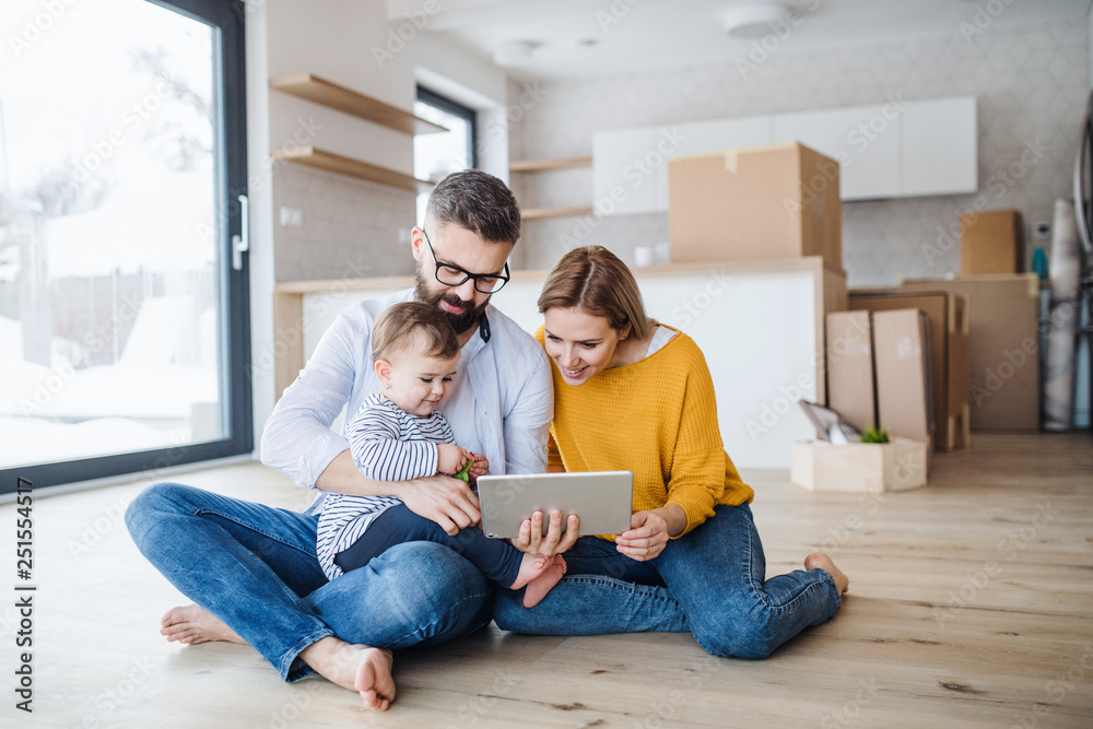 A young family with a toddler girl moving in new home, using tablet. A young family with a toddler girl moving in new home, using tablet.
