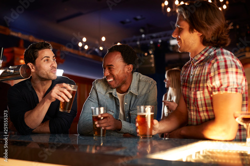 Group Of Male Friends Drinking Beer In Bar Together