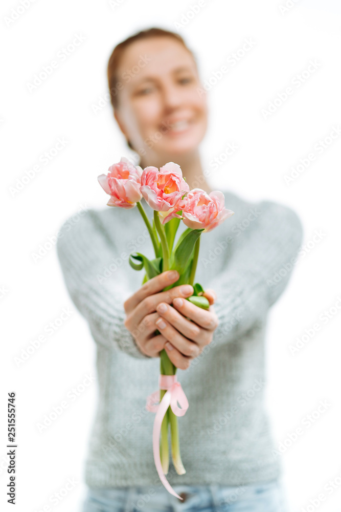 Young beautiful woman gives pink tulips on white background.