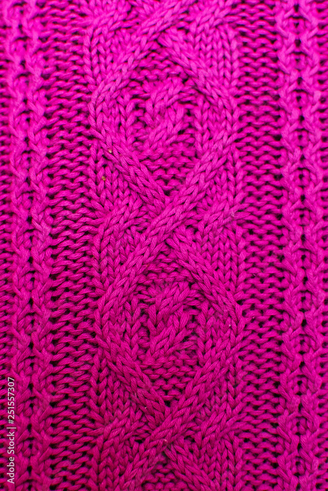 Knit texture of pink wool knitted fabric with cable pattern as background. Magenta texture.
