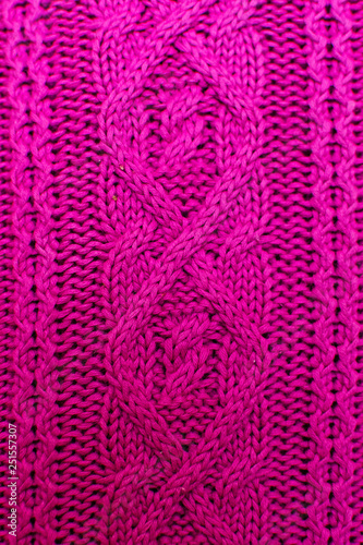 Knit texture of pink wool knitted fabric with cable pattern as background. Magenta texture.