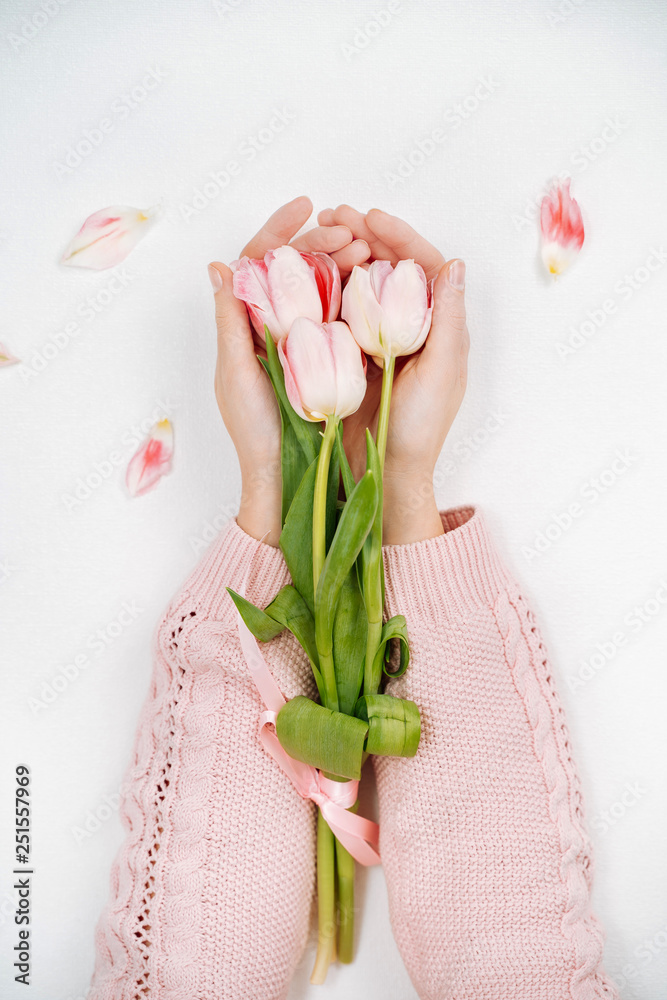 Young girl holding a bouquet of pink tulips. Top view, white background.