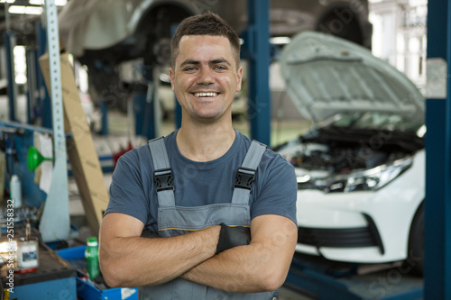 Portrait of positive male worker enjoying his job at car service. Qualified smiling man in uniform with folded arms looking at camera and posing. Concept of happiness and work satisfaction.