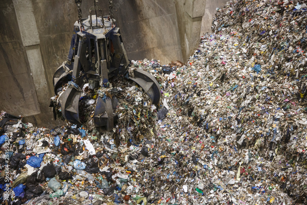 Mechanical claw hand grabbing pile of mixed waste