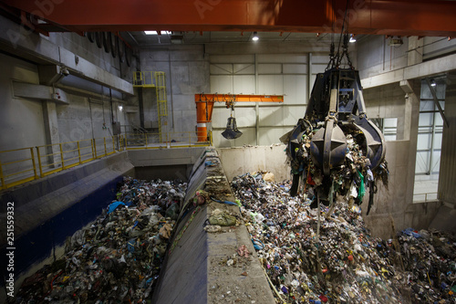 Mechanical claw hand grabbing pile of mixed waste photo