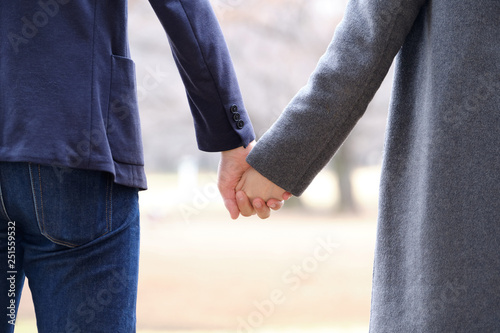 冬の公園で小指をつなぐ男女のカップル