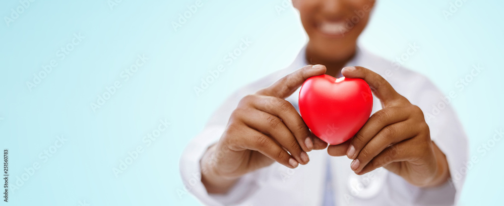 health, medicine and charity concept - close up of african american female doctor hands holding red heart over blue background health, medicine and charity concept - close up of african american female doctor hands holding red heart over blue background