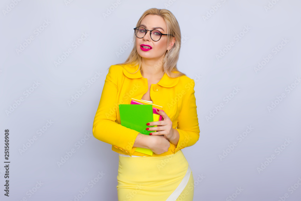 Woman in yellow suit holding books in her hands Woman in yellow suit holding books in her hands