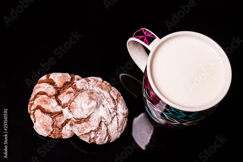 Chocolate cookies with a cup of milk on a black background