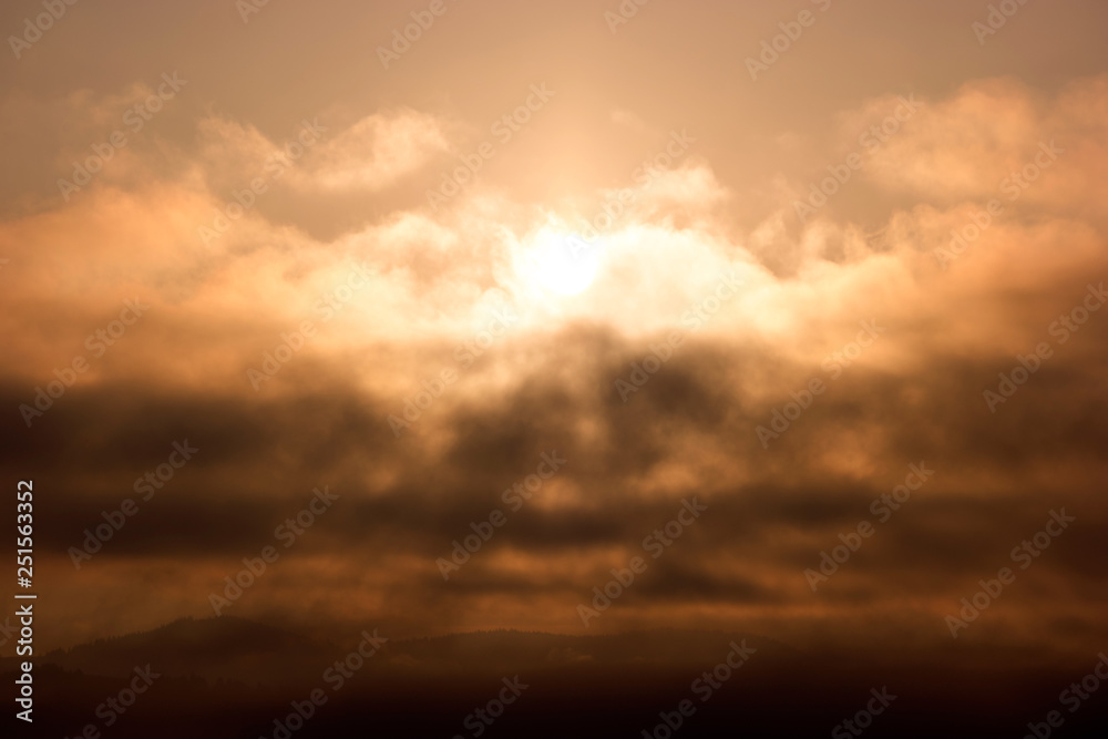 Cloudy sky at dawn. Colorful scenic landscape with mountains, yellow and orange sky with clouds. Morning sunrise in mountains.