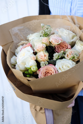 Bouquet of white and beige Roses. Woman Florist holding bouquet of Flowers indoor. Female florist preparing bouquet in flower shop. Close up. Mother's Day and Valentine's Day concept