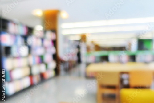 Blurred of the interior of the public library with wooden tables, chairs and books in bookshelves. Education and book's day background concept.