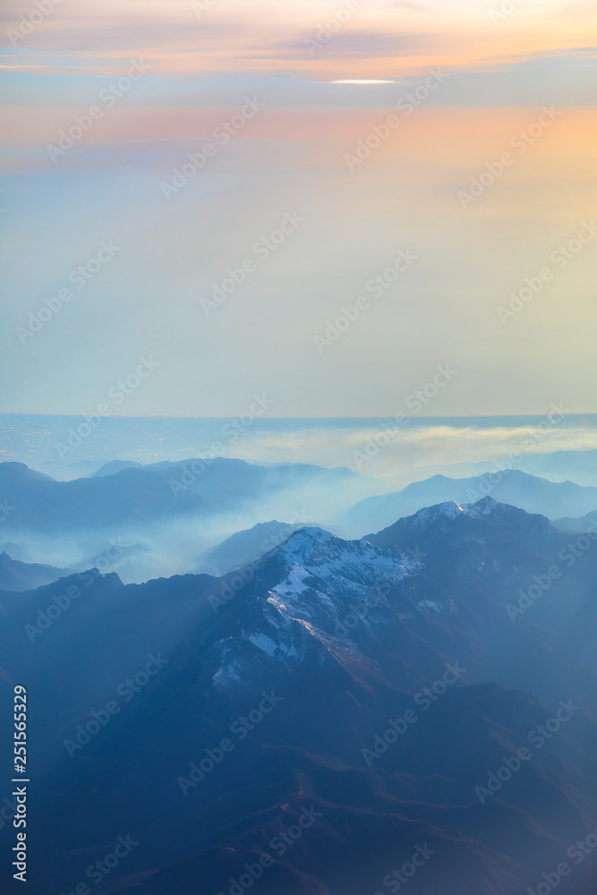 Aerial view over the Mediterranean sea and blue Alps Mountains with soft sunset light