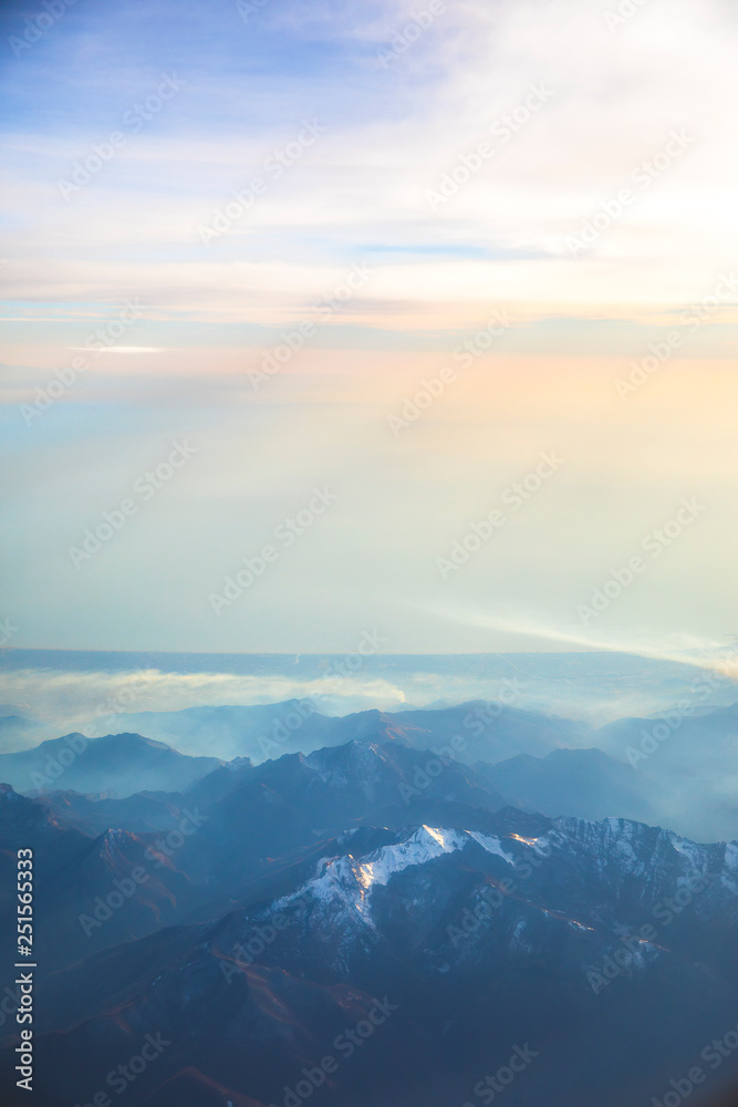 Aerial view over the Mediterranean sea and blue Alps Mountains with soft sunset light