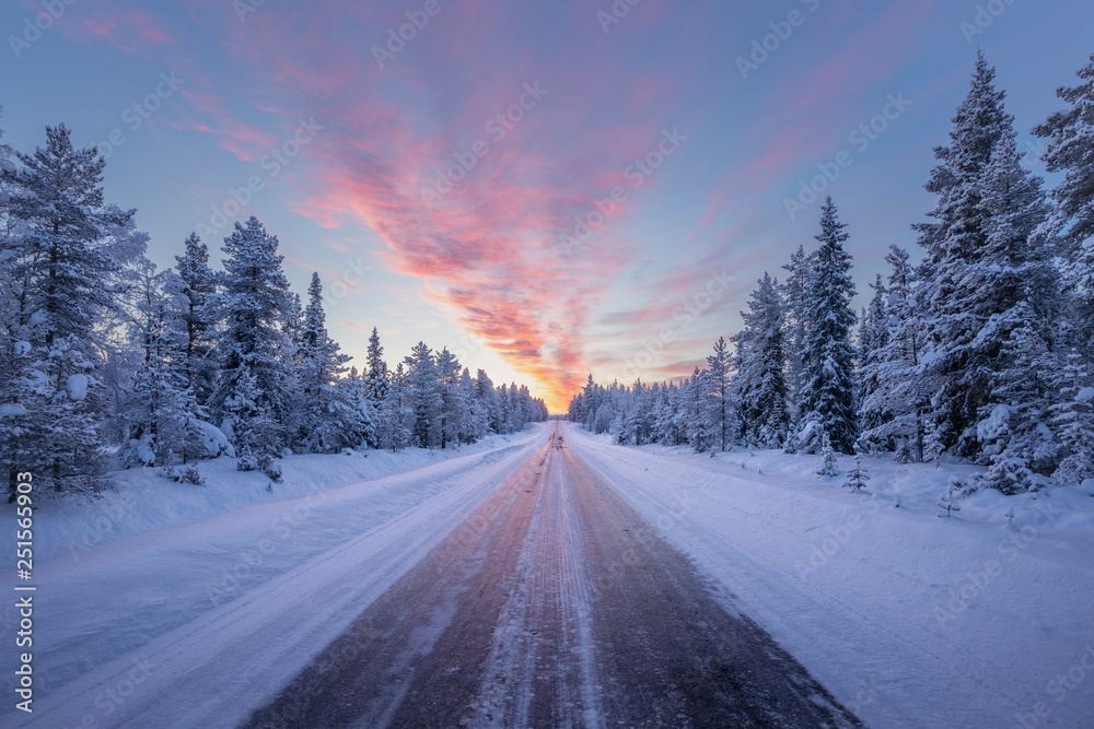 Road leading towards colorful sunrise at winter in Finland - obrazy, fototapety, plakaty 