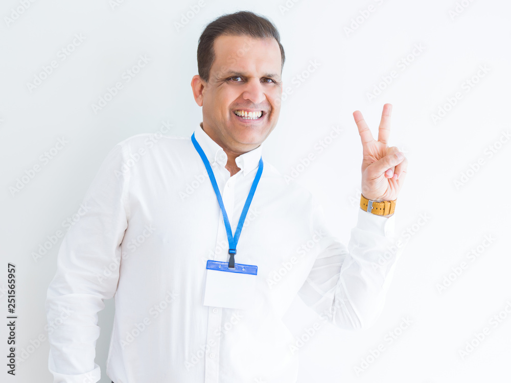 Middle age business man wearing ID card over white background smiling with happy face winking at the camera doing victory sign. Number two. Middle age business man wearing ID card over white background smiling with happy face winking at the camera doing victory sign. Number two.