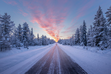 Road leading towards colorful sunrise at winter in Finland
