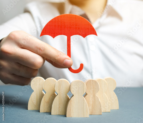 Boss holding a red umbrella and defending his team with a gesture of protection. Security and safety in a business team. Life insurance. Customer care, care for employees. Selective focus photo